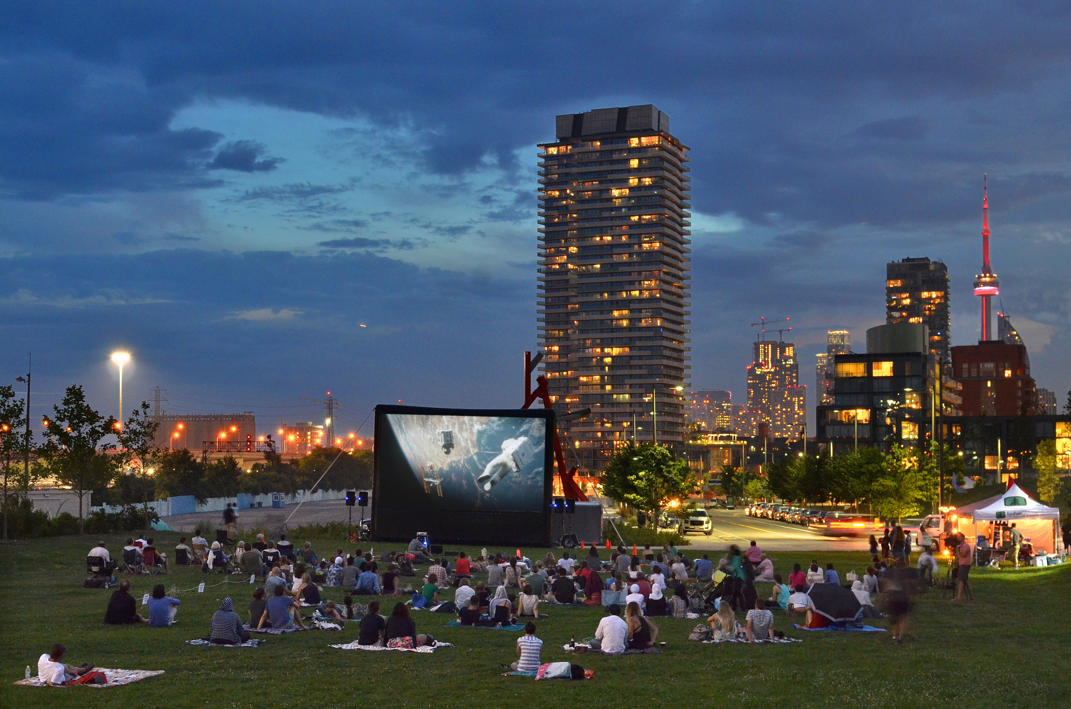 A crowd gathered on the south lawn at Corktown Common last summer for an open-air movie screening with the downtown skyline behind.