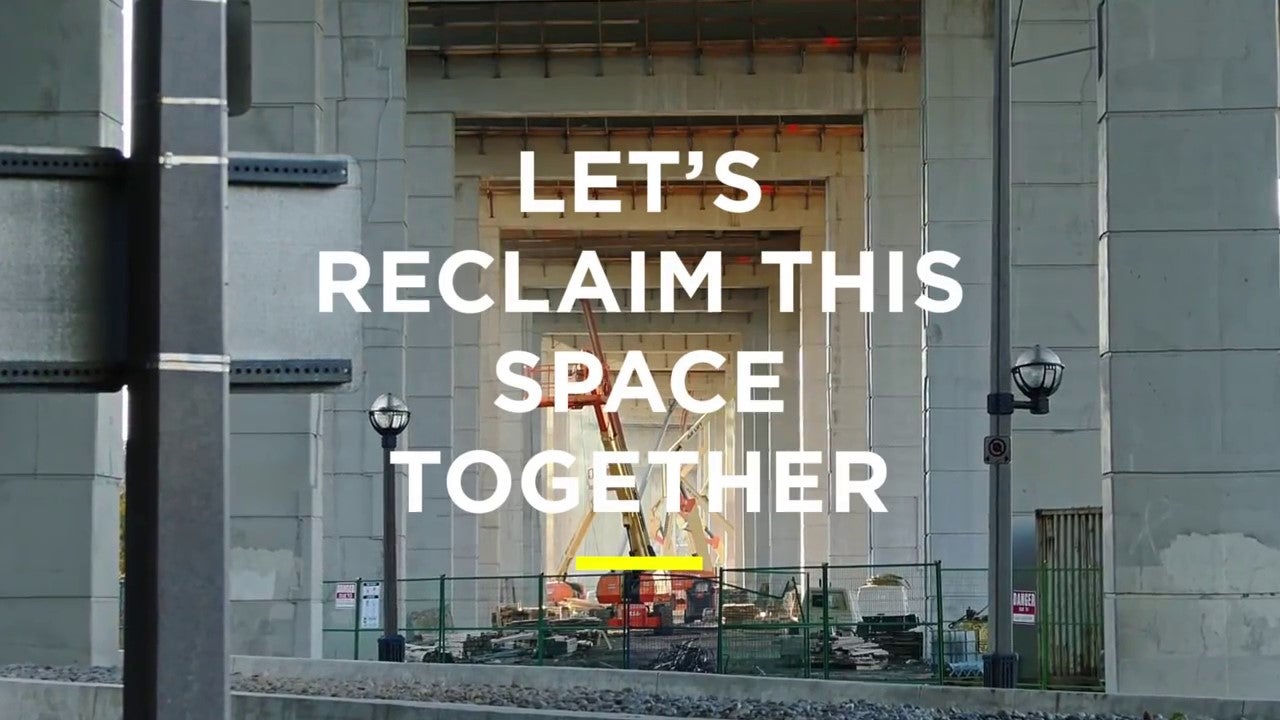 Image description: Looking through the the columns supporting the Gardiner Expressway, there is an active construction site in the background. Block text reads &quot;Let's Reclaim This Space Together.&quot;