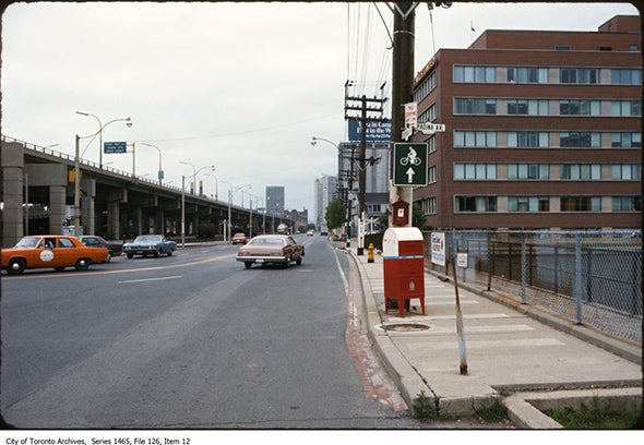 cars along a waterfront street in the 1970s