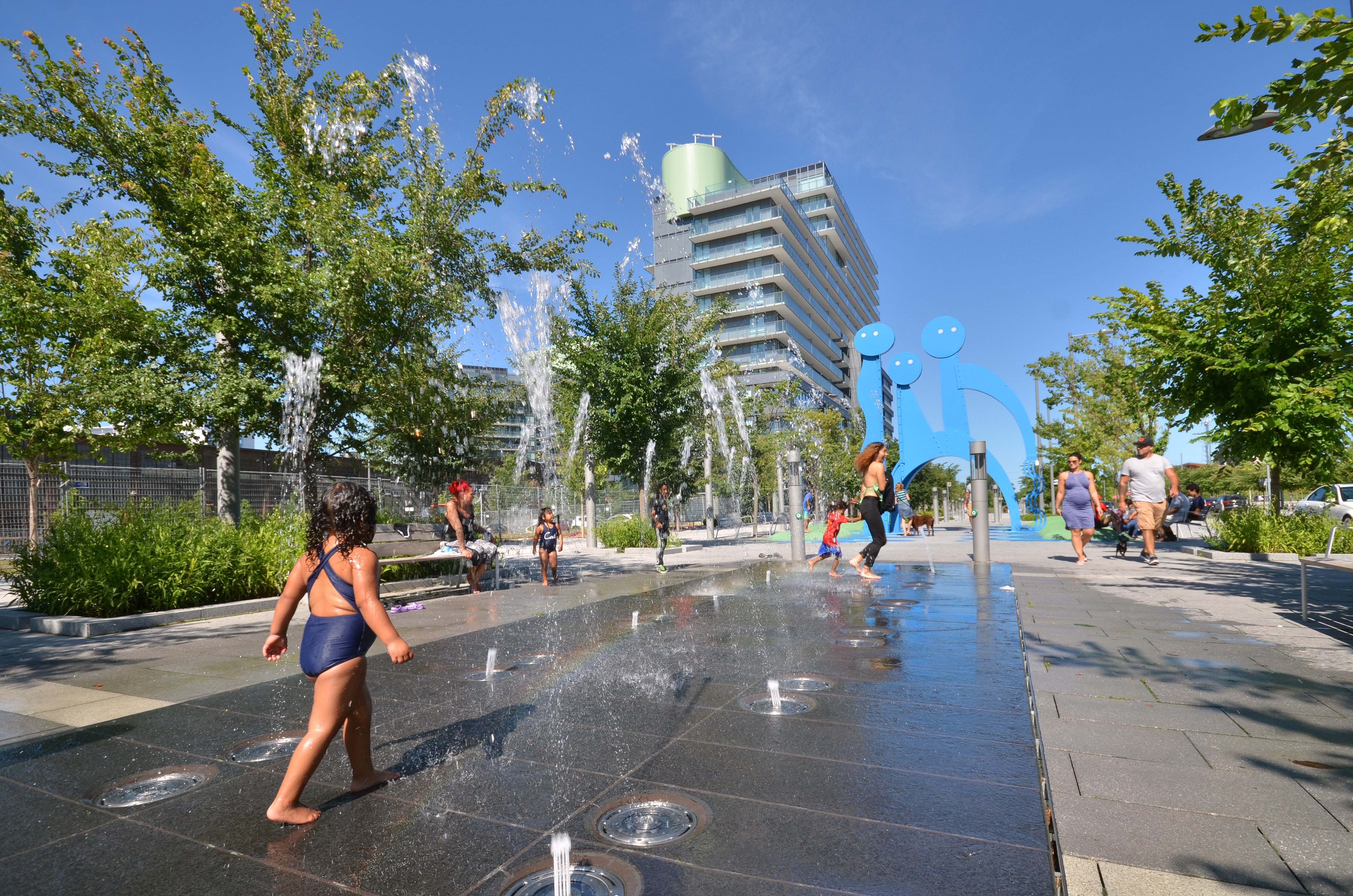 Children running through the splash pad on the Front Street Promenade in the West Don Lands.