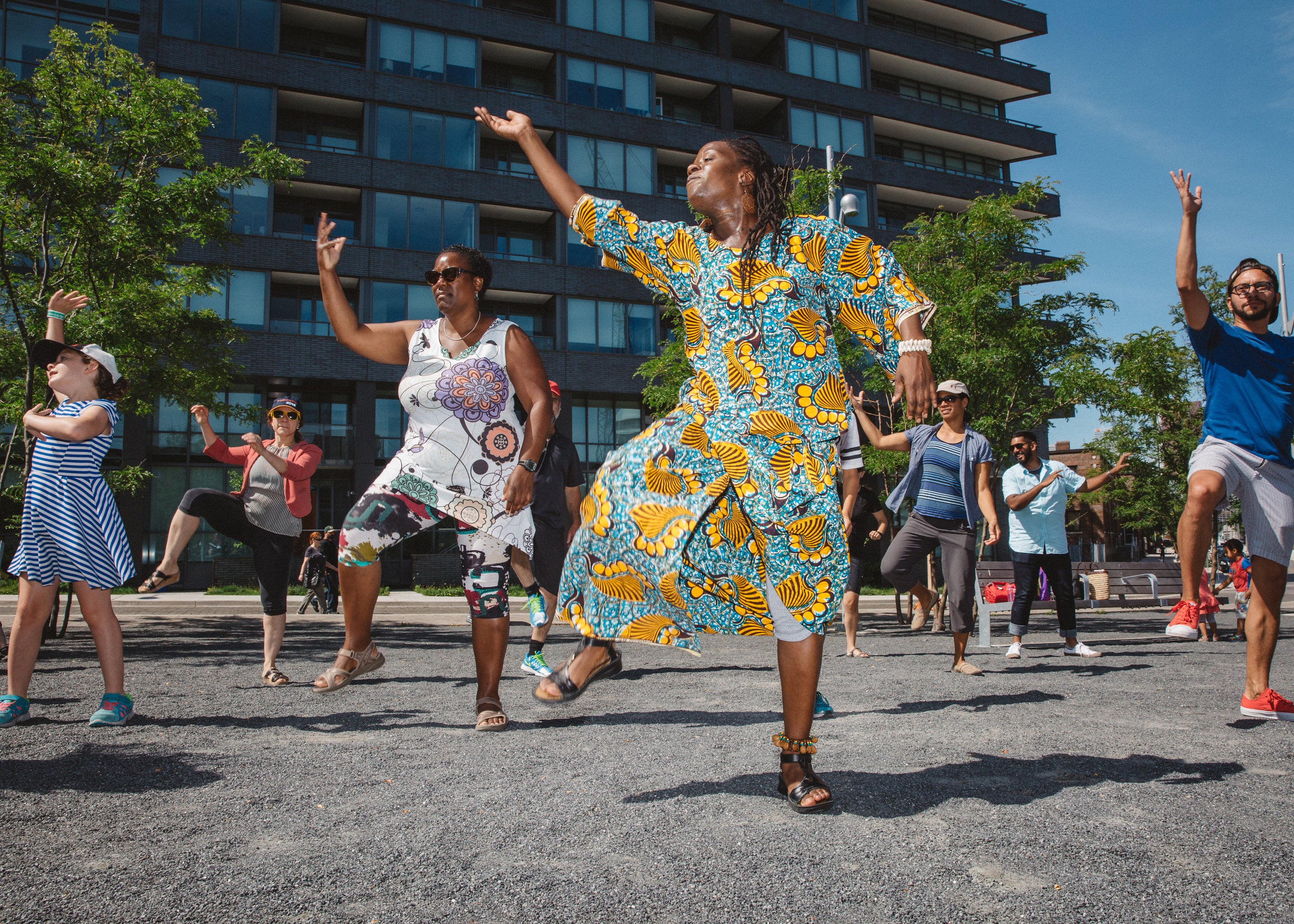 Community members at Lawren Harris Square learning the West African Dance from Miss Coco.