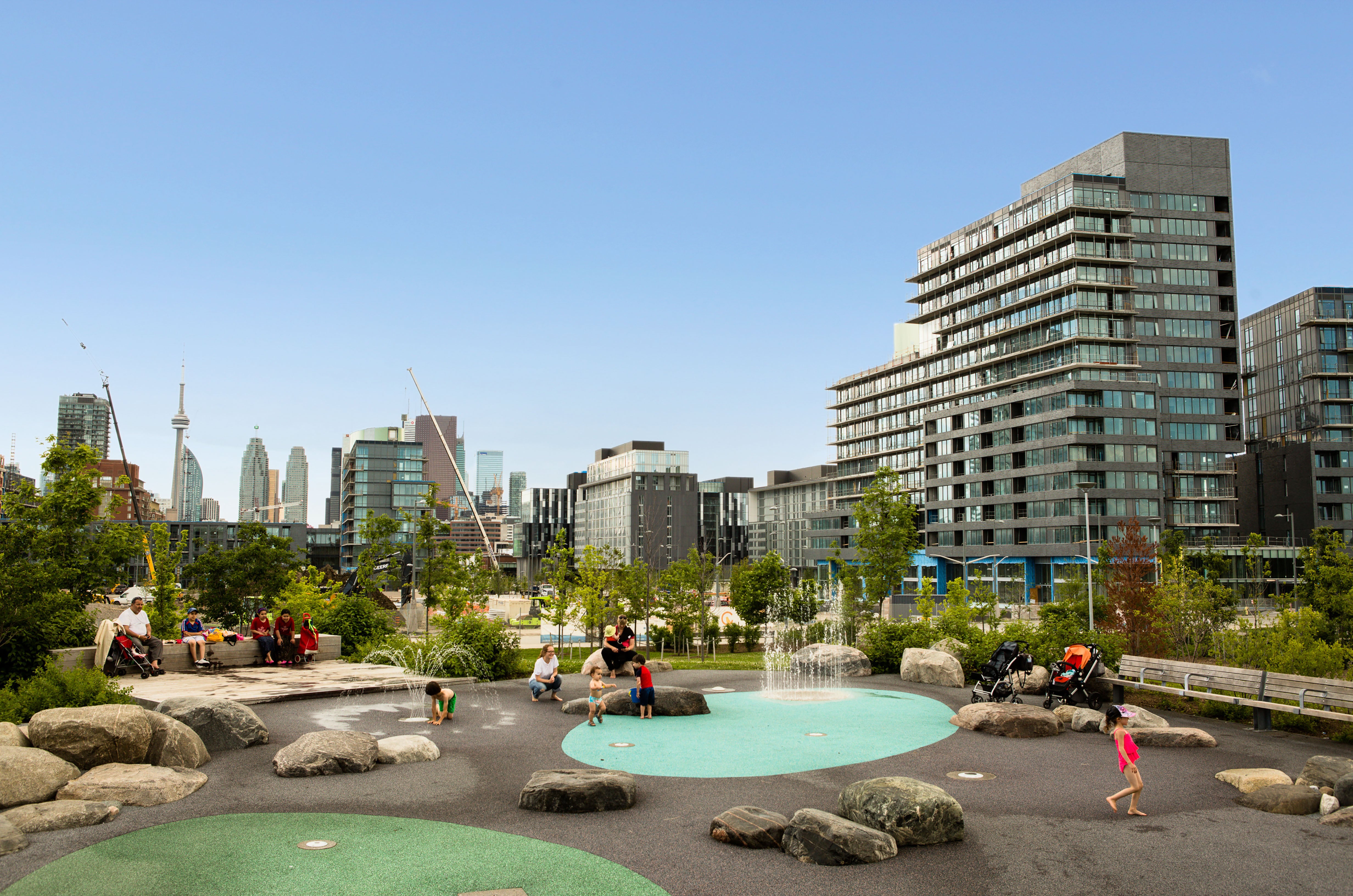 People at play on the splash pad overlooking the downtown skyline.