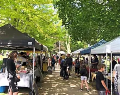 rows of tents set up under trees at a farmers market