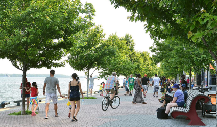 people on bikes and walking on boardwalk beside water