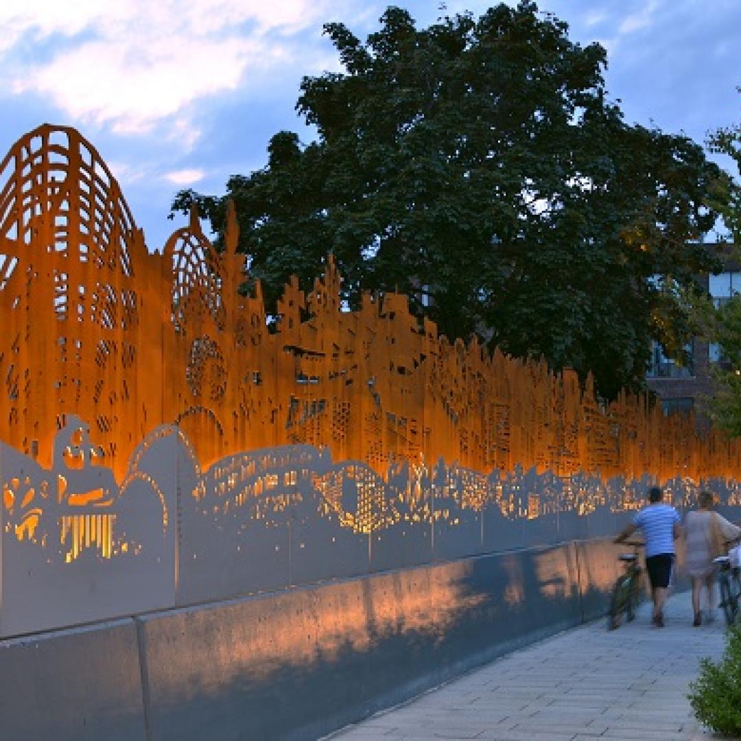 people walking on a sidewalk next to public art