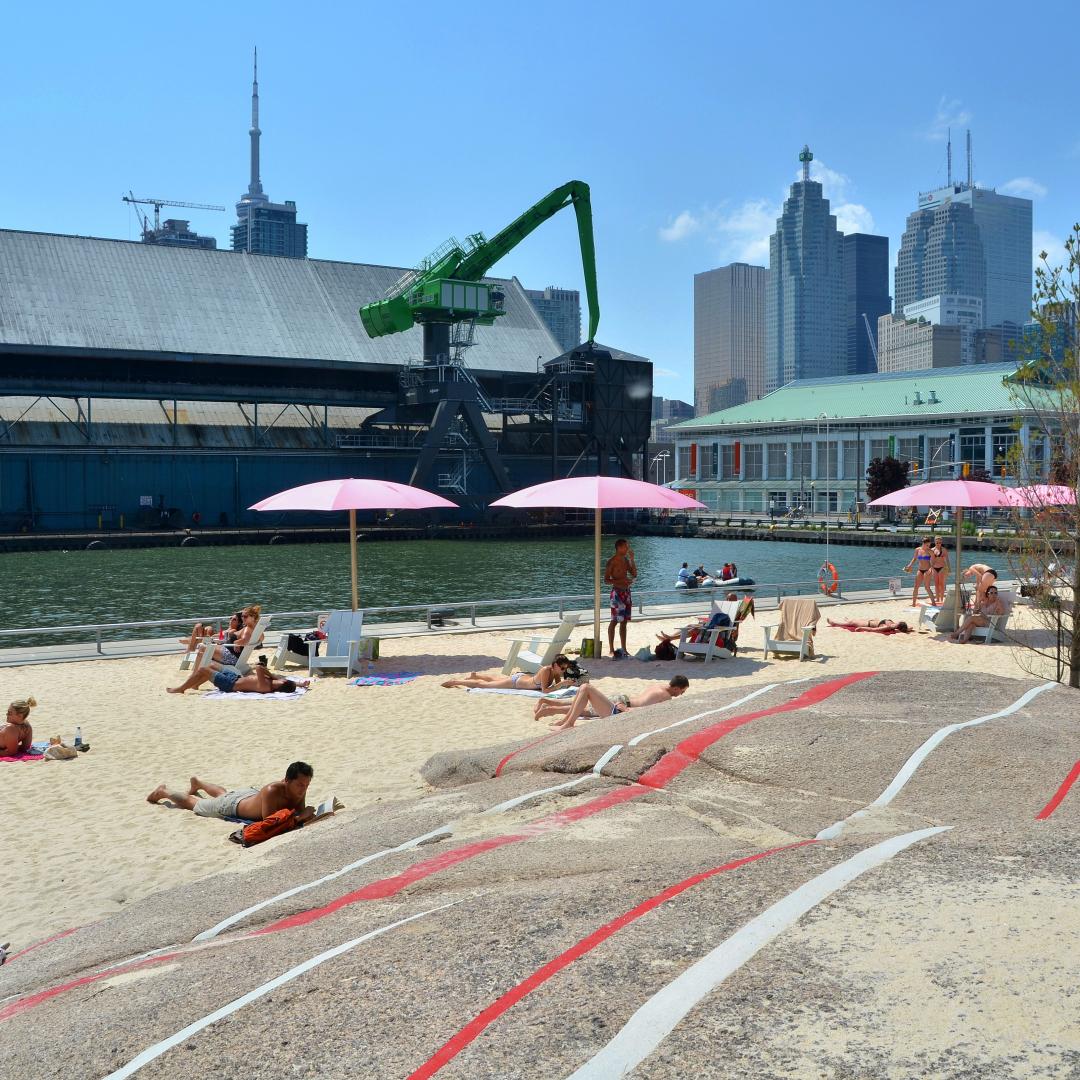 the sandy beach, rocks, and pink umbrellas at Sugar Beach