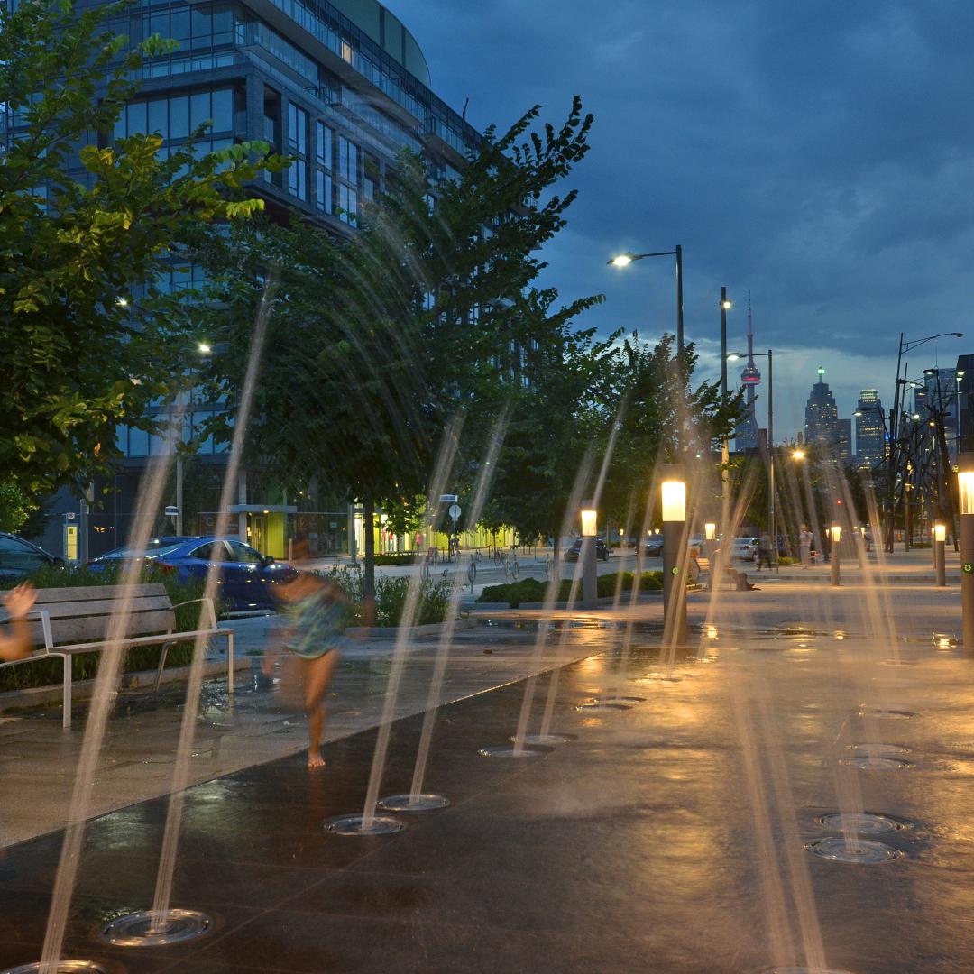 children playing next to street fountains at night