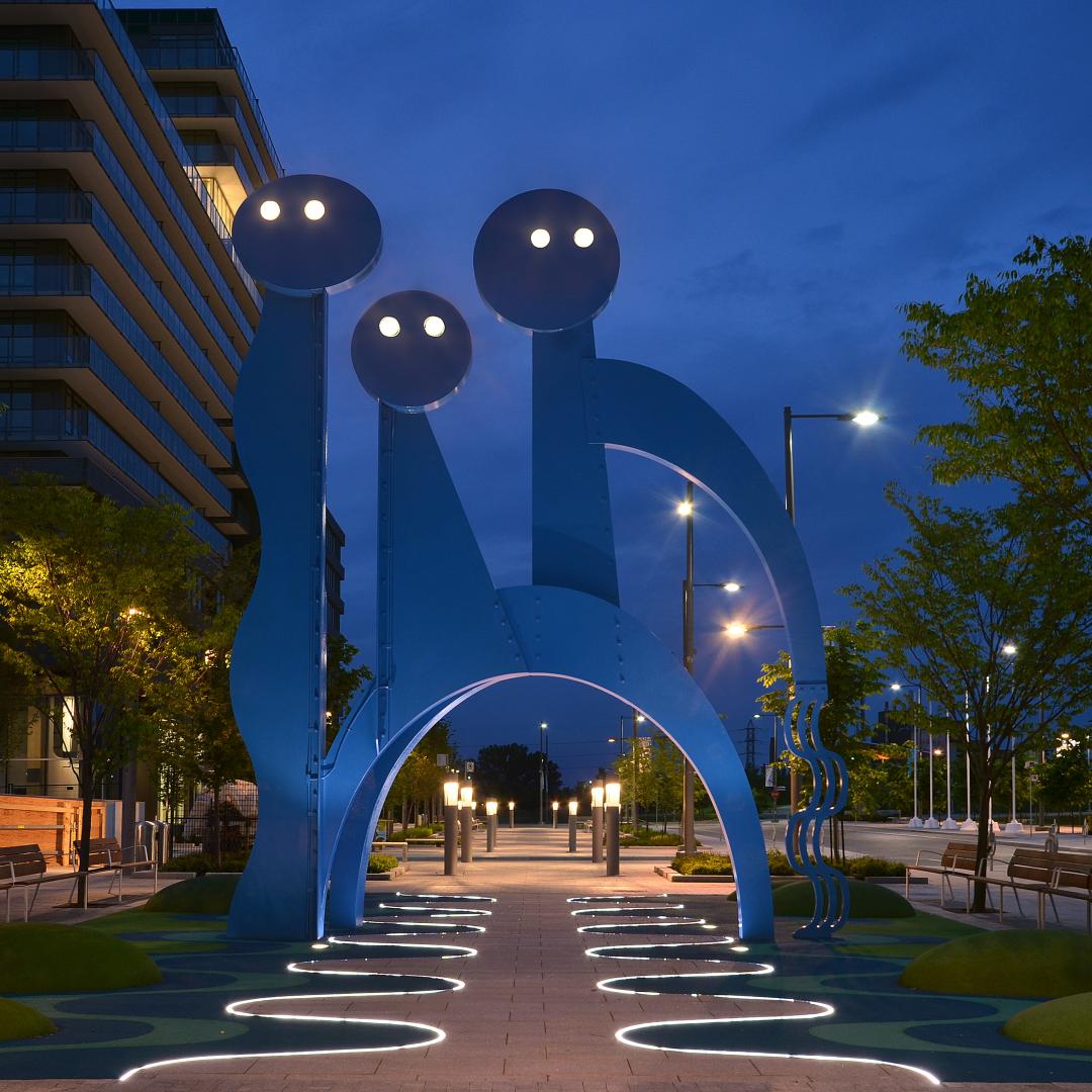 a night image of The Water Guardians public art piece with lights on