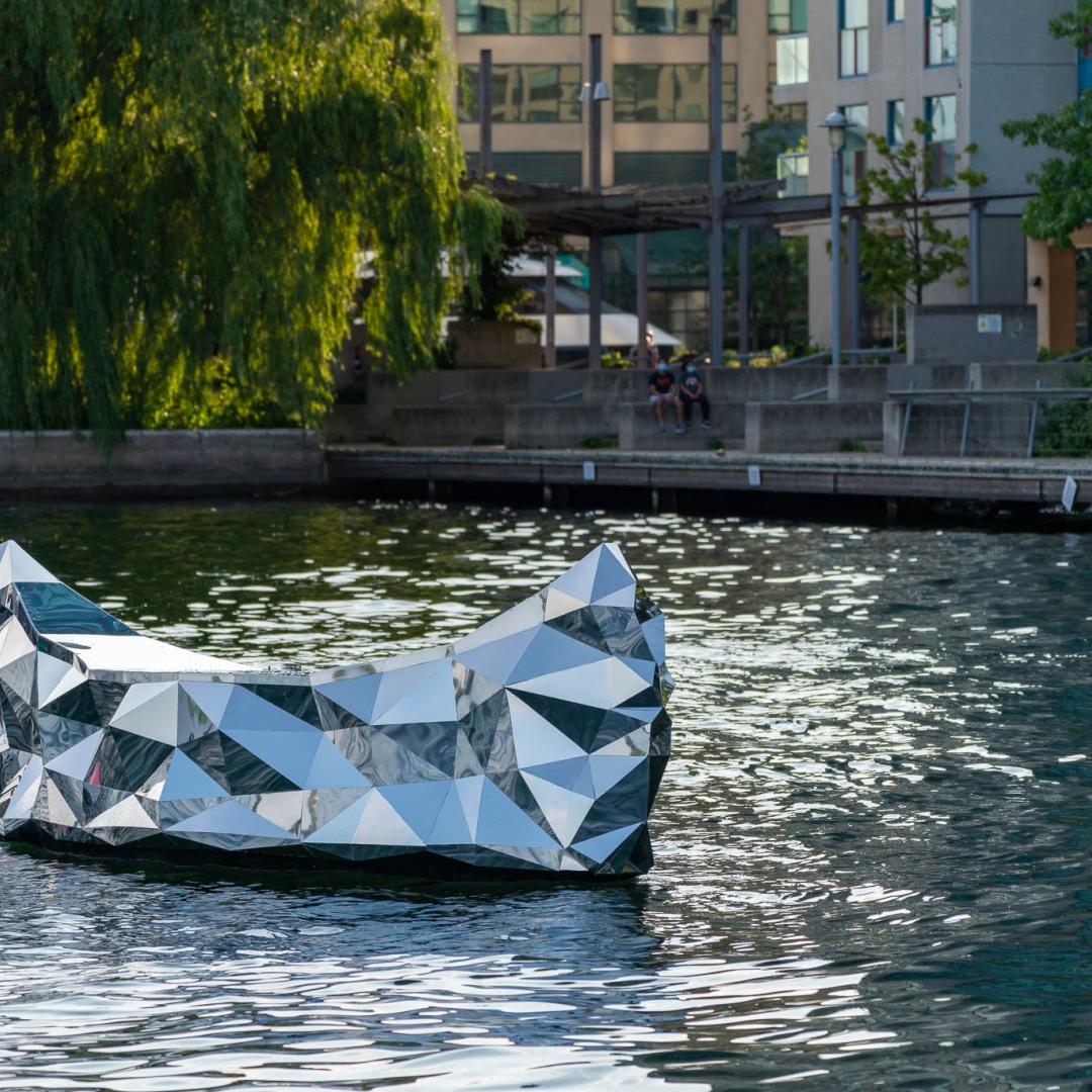 a photo of a floating public art piece that resembles a mirrored canoe in Lake Ontario 