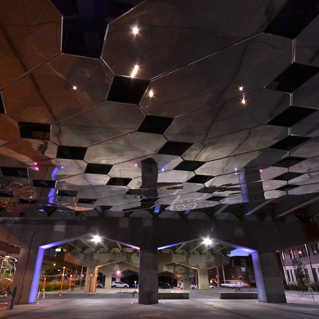 a view of the underpass park lit up at night time and mirror reflection of the public art installation