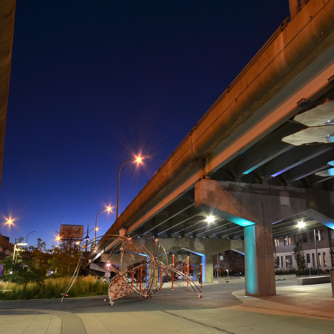 a glimpse of the night sky between the park play structure and overpasses above