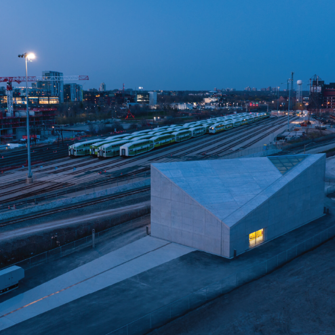 Aerial photo of an angular building at dusk with a railyard in the background.