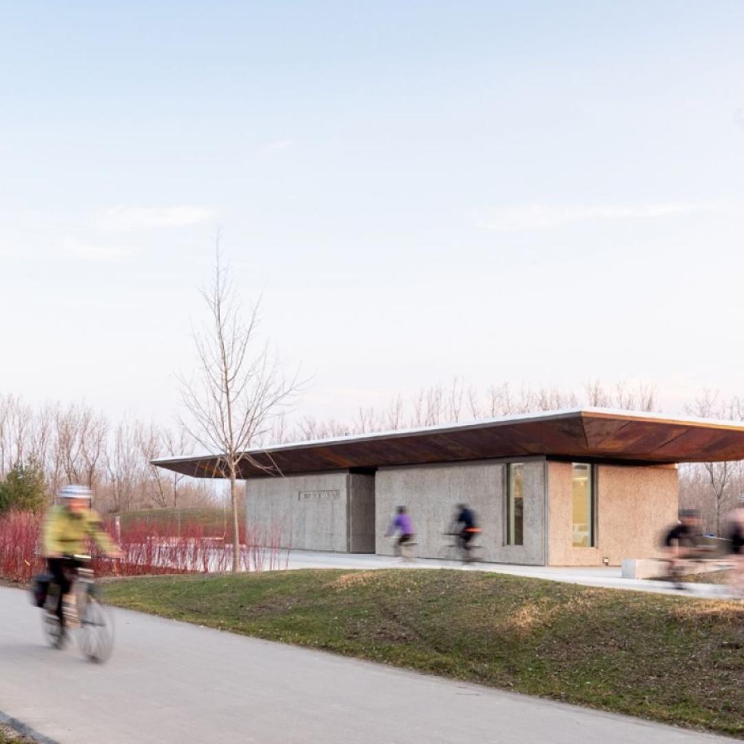 A park entrance and pavilion with pedestrians passing by. 