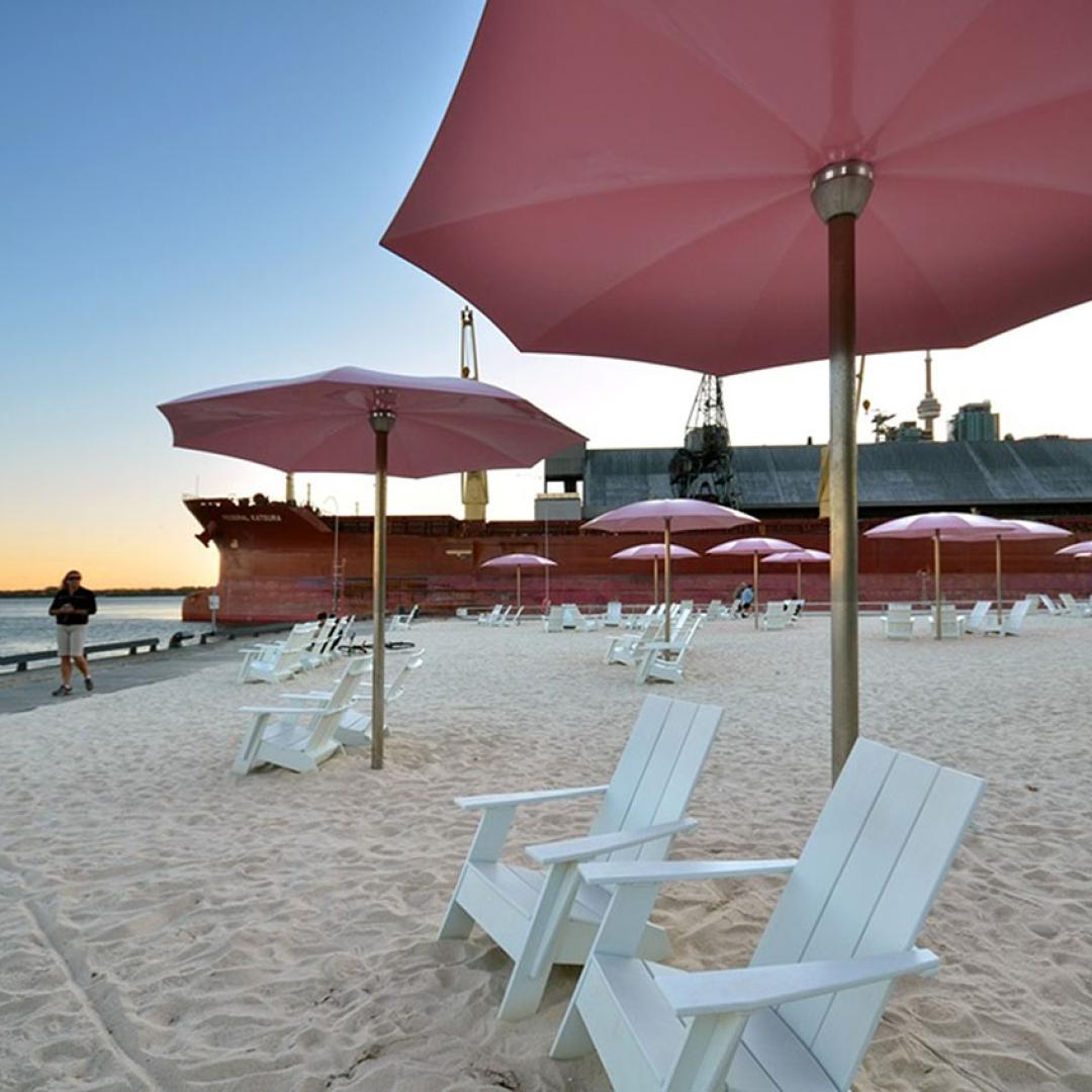 White chairs under a pink umbrella on a beach. 