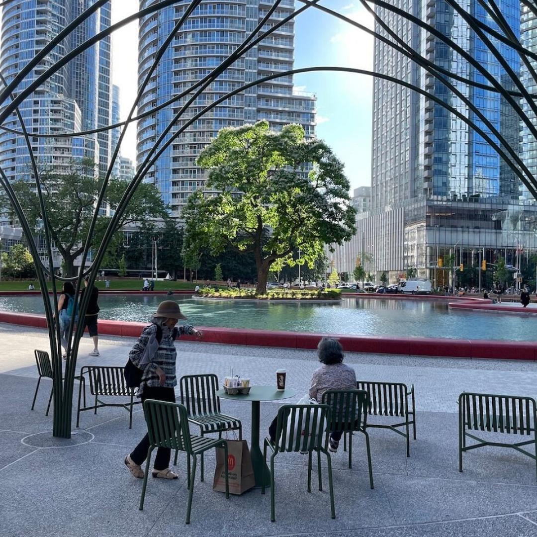 people under a trellis next to a park pond