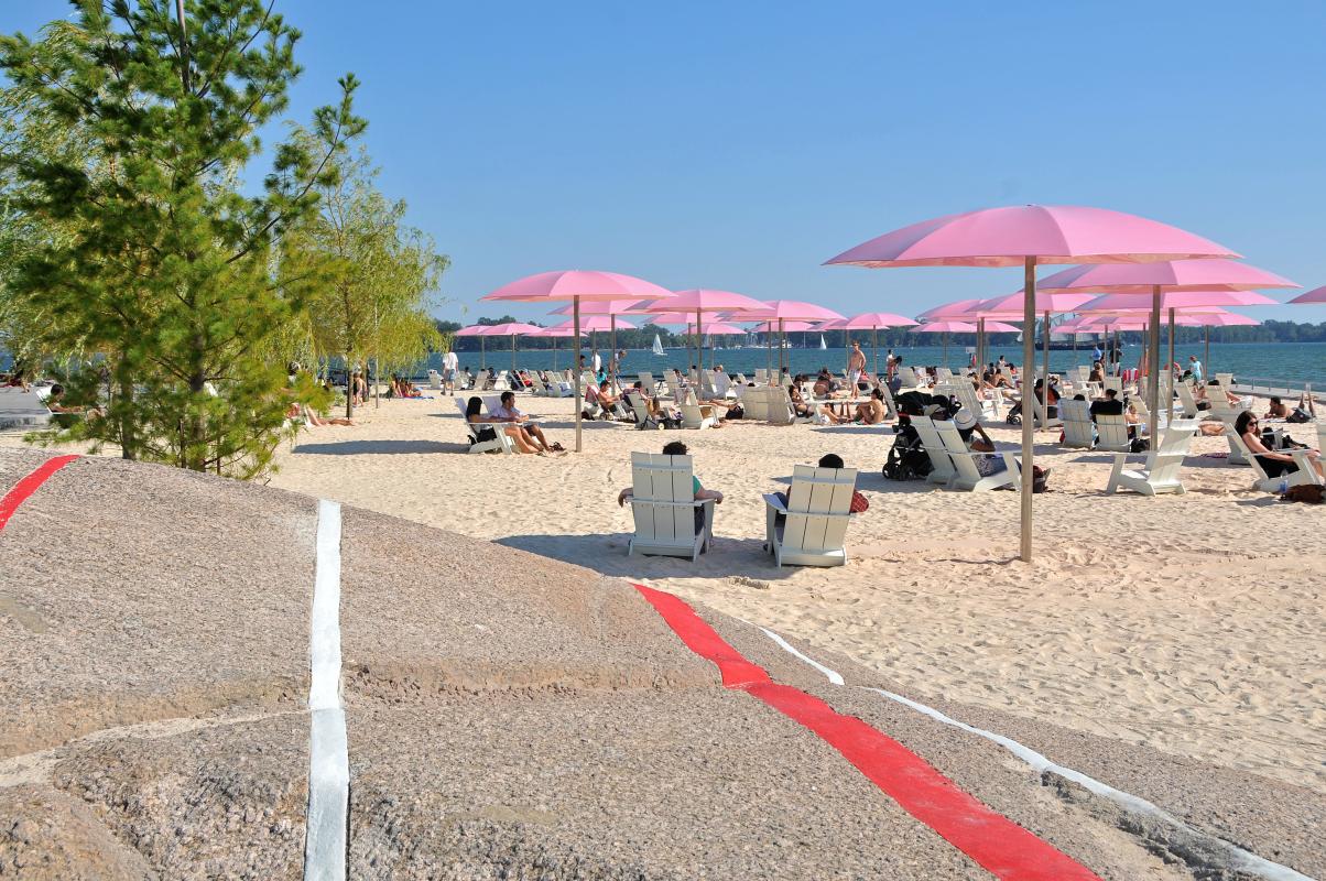 pink umbrellas and a sandy beach next to Lake Ontario