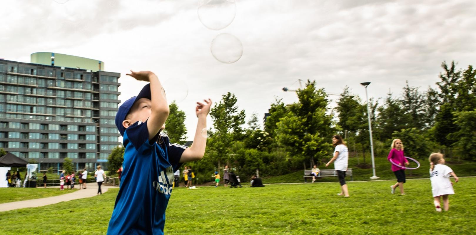 children playing and chasing bubbles on the lawn at Corktown Common