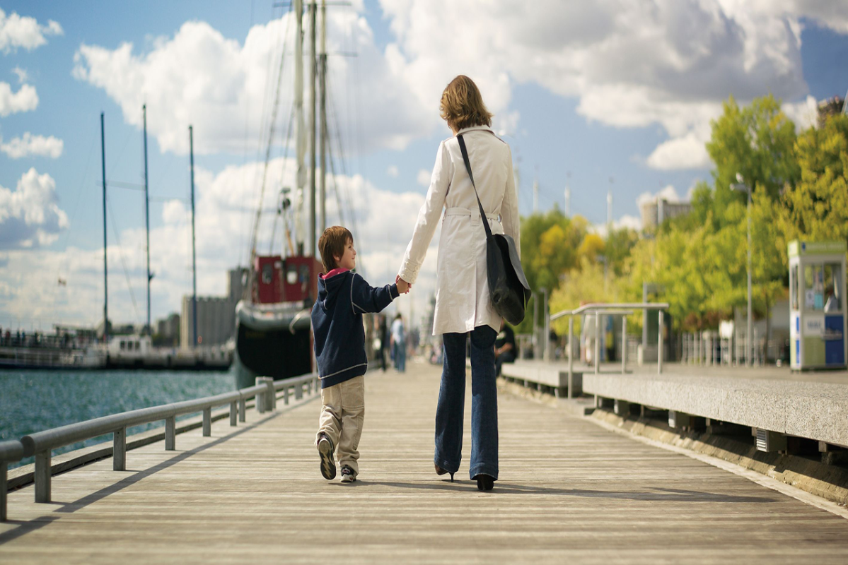 image of mother and son holding hands and walking along the water's edge boardwalk