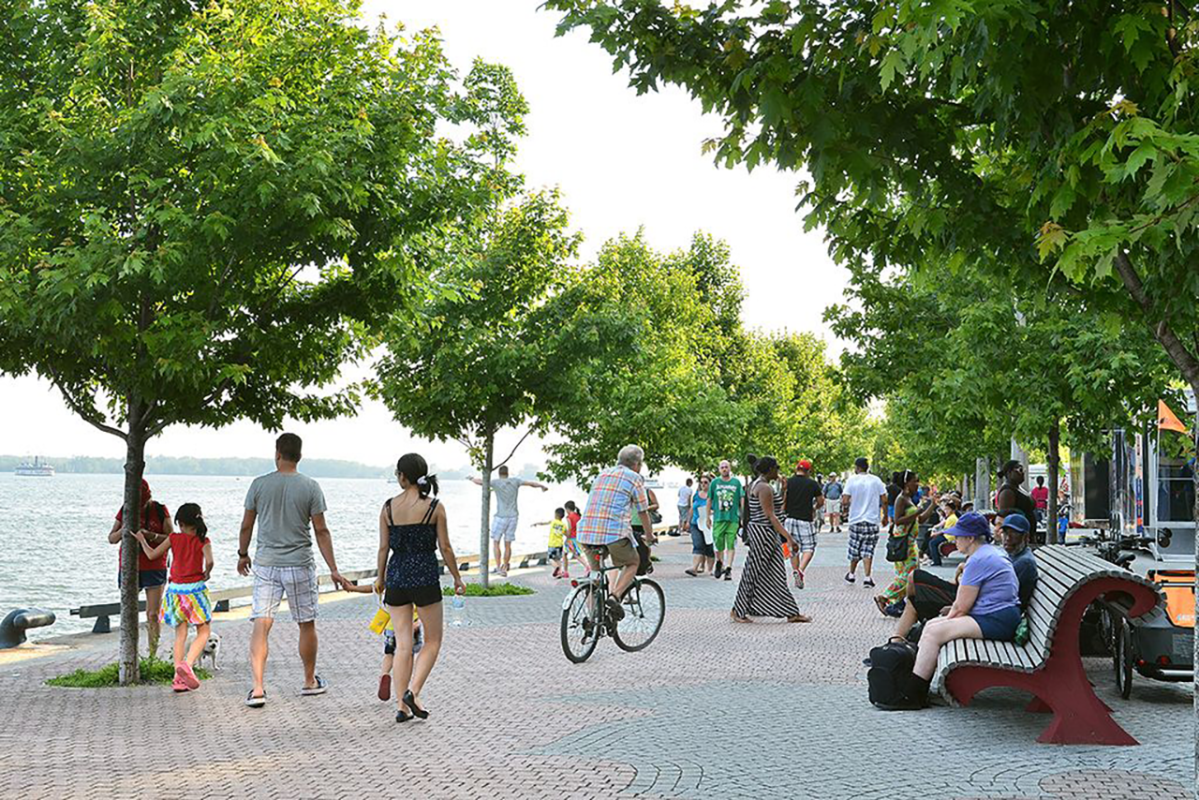 people on bikes and walking on boardwalk beside water