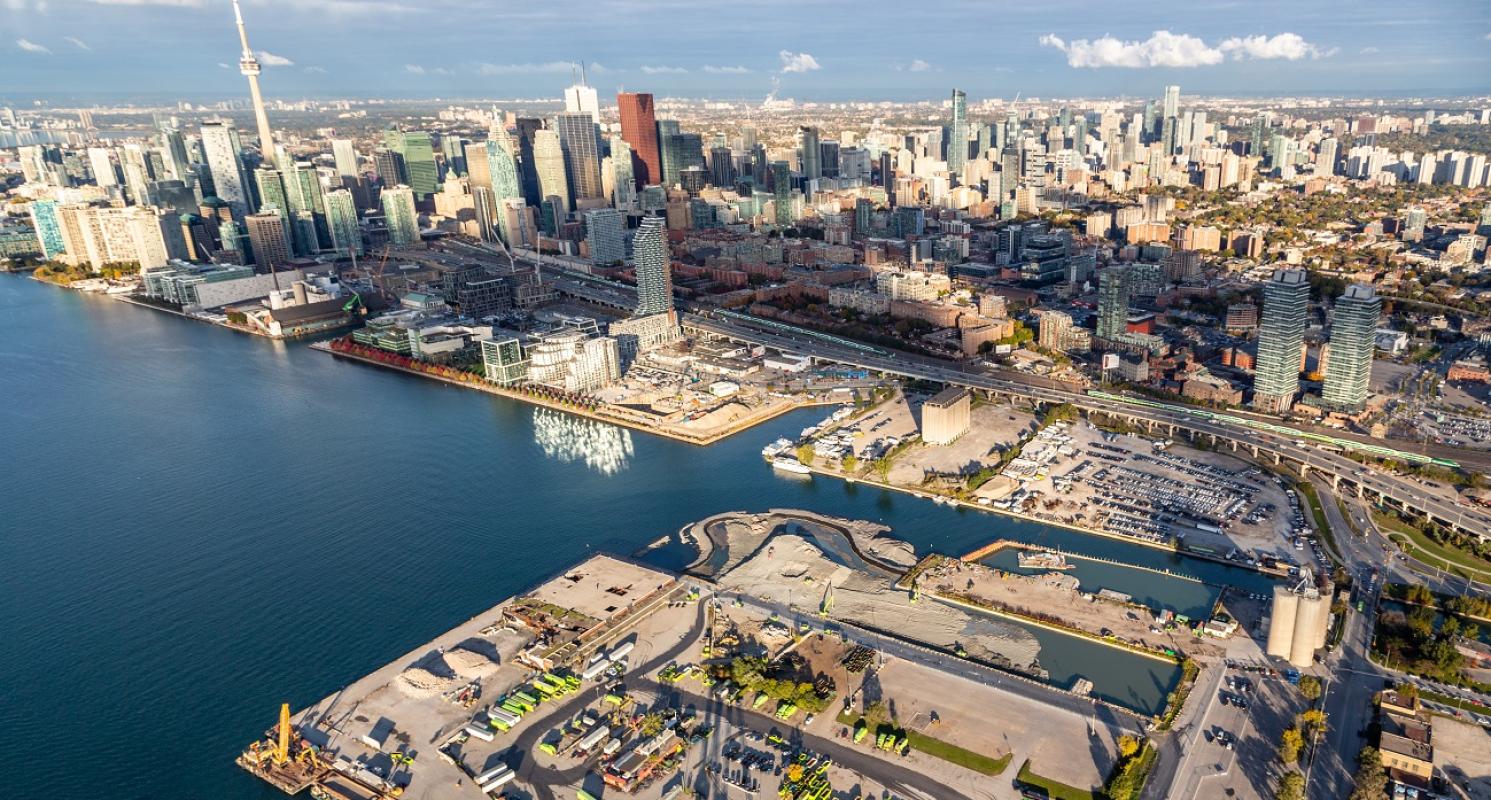 aerial image taken from over the Port Lands looking at East Bayfront, the central waterfront and the downtown core showing Lake Ontario and buildings
