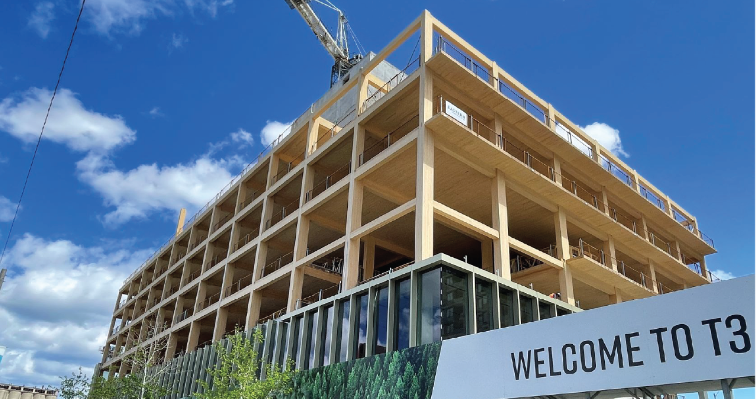 A mass-timber building under construction. Timber frame in foreground and blue sky in background.