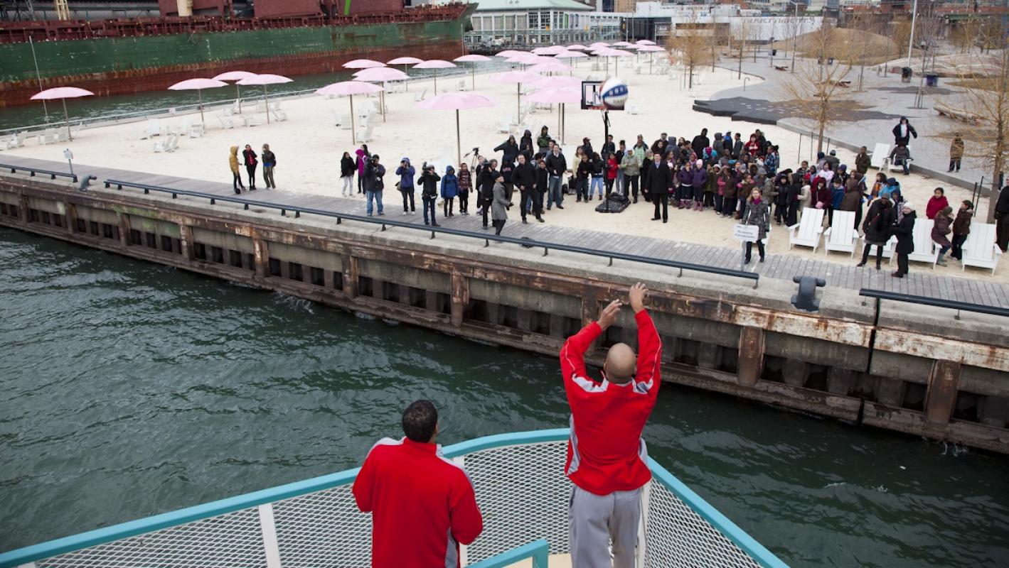 Harlem Globetrotters shooting basketballs to a group of people gathered on the water's edge