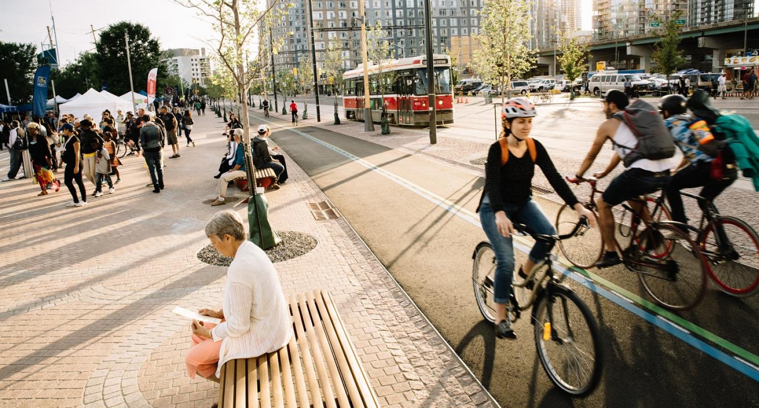 cyclists using a mulit-use trail and people sitting along the new street benches