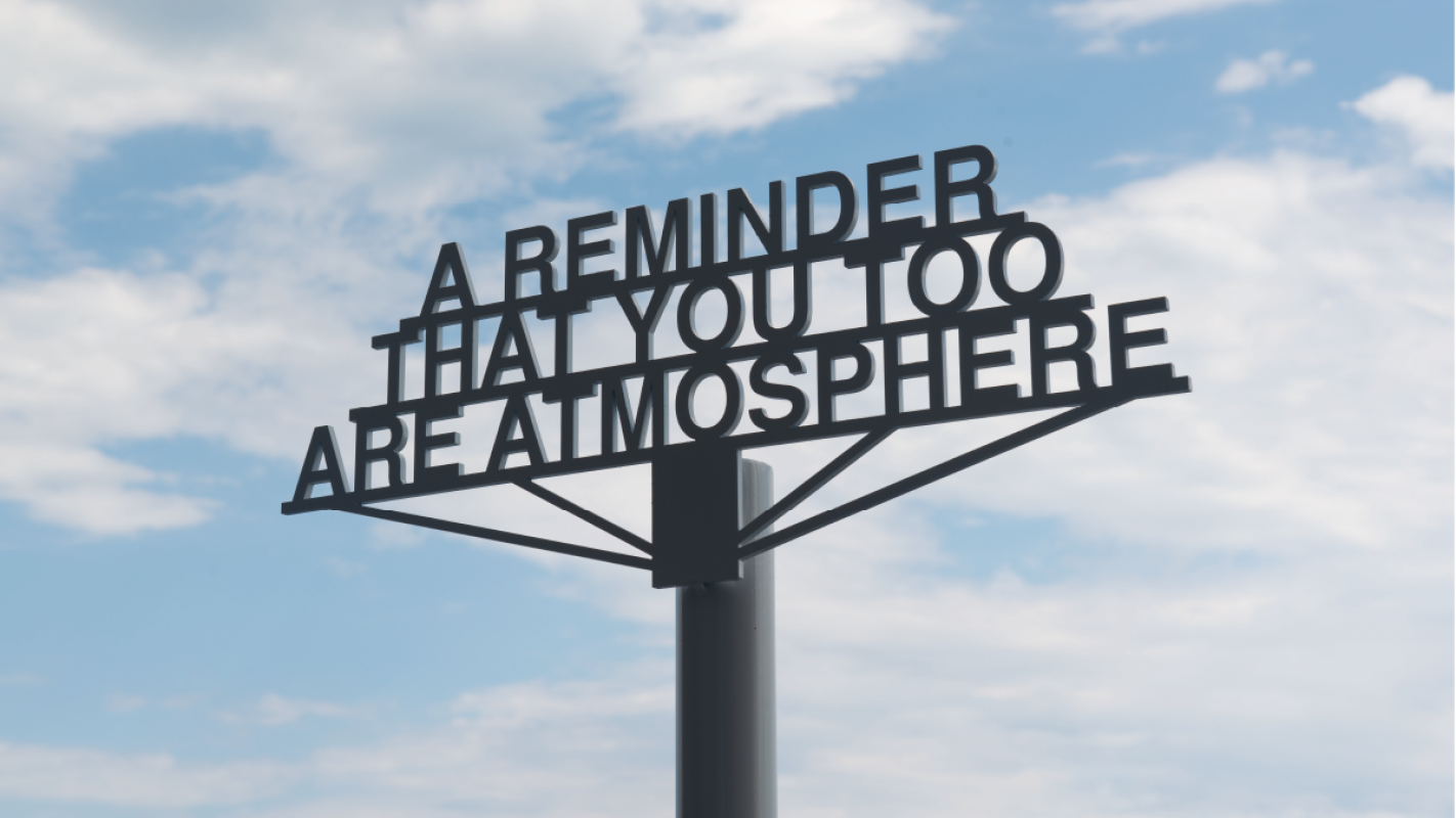 A metal sign reads: a reminder that you too are atmosphere