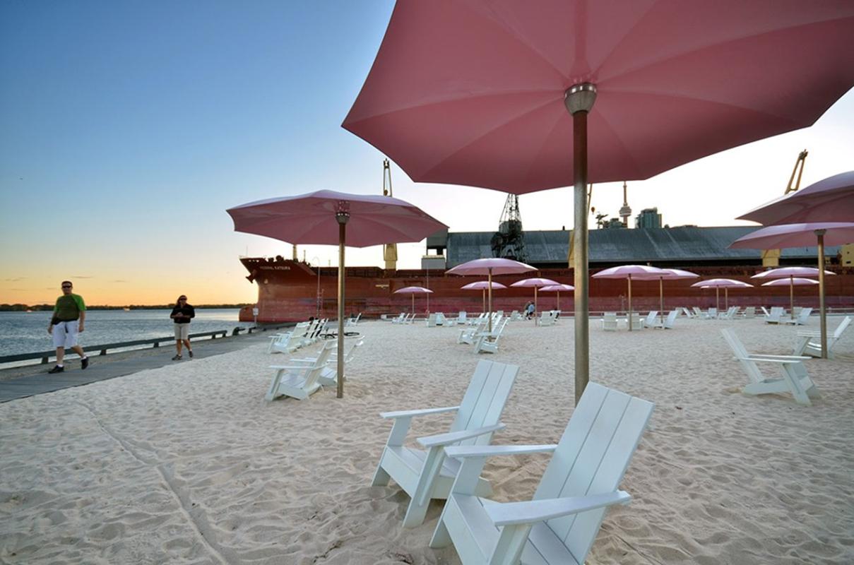 White chairs under a pink umbrella on a beach. 