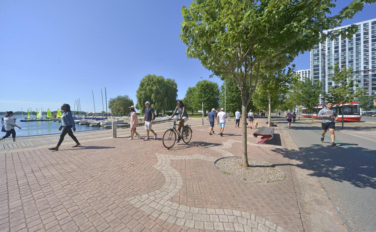 people walking along a waterfront promenade on a sunny day