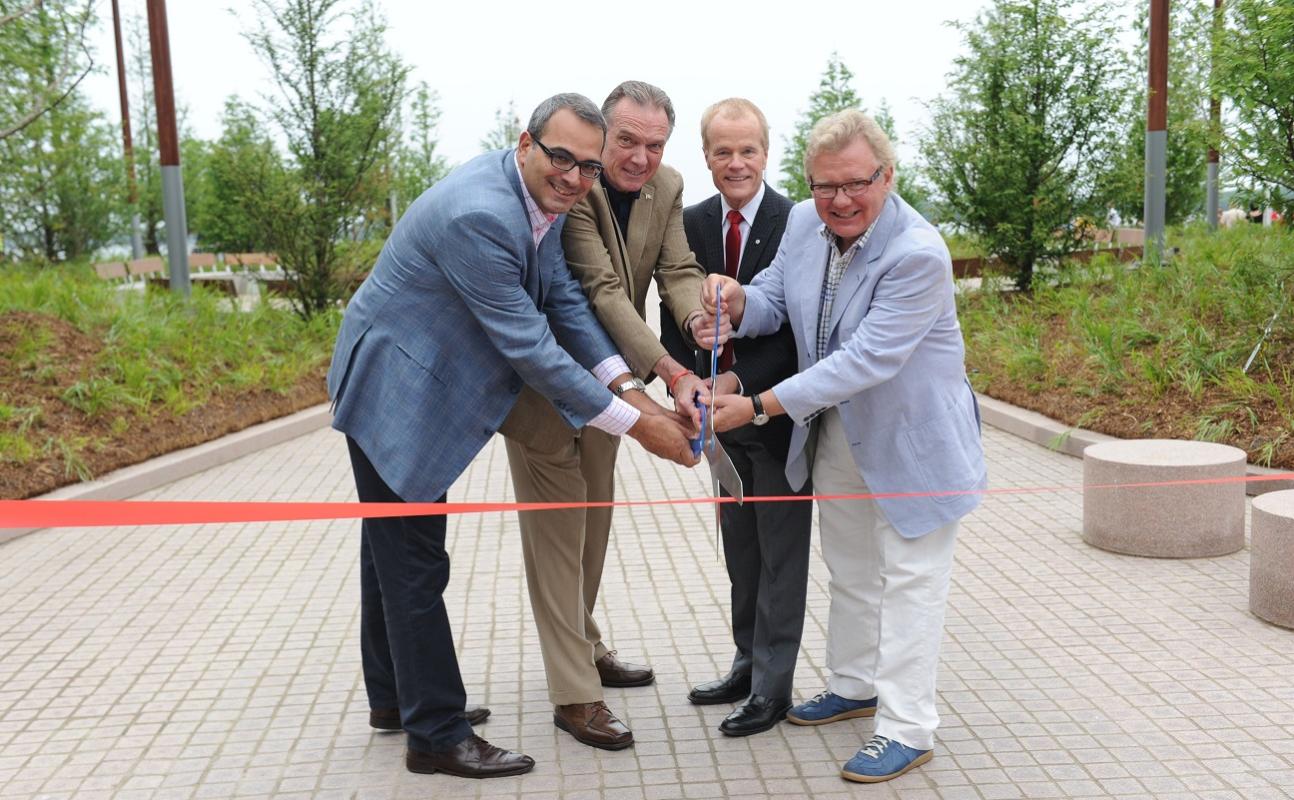 a group of officials at an outdoor ribbon cutting ceremony