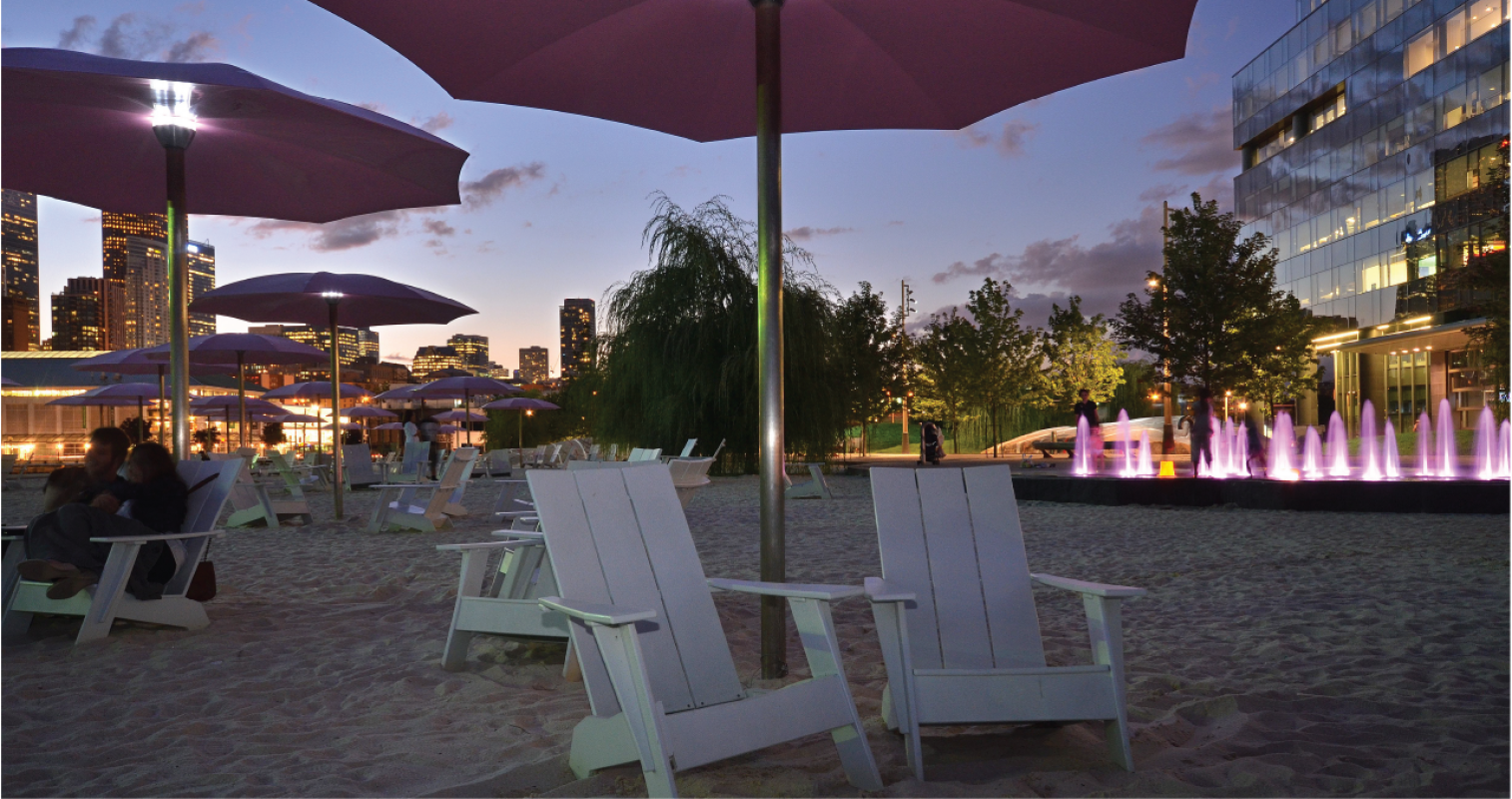 Illuminated pink umbrellas at Sugar Beach at night with the cityscape in the background.. 