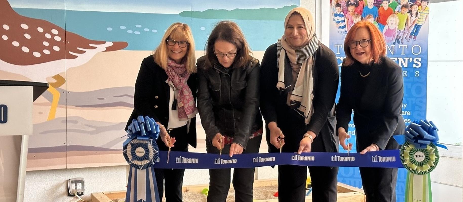 four women cutting the ribbon at an opening celebration