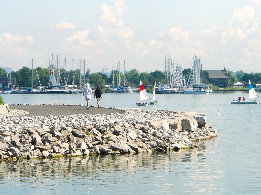 a waterfront trail with pebble shoreline and boats in the lake