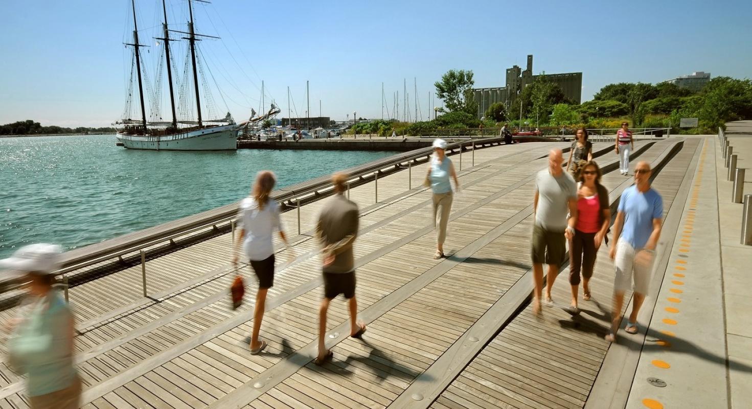 people strolling along a wooden wavedeck next to Lake Ontario