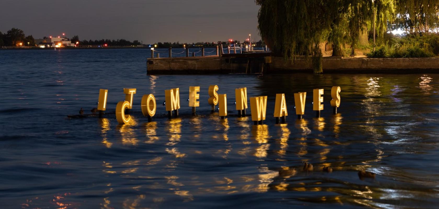 Letter IT COMES IN WAVES float and glow on water in the dark as part of a floating artwork.