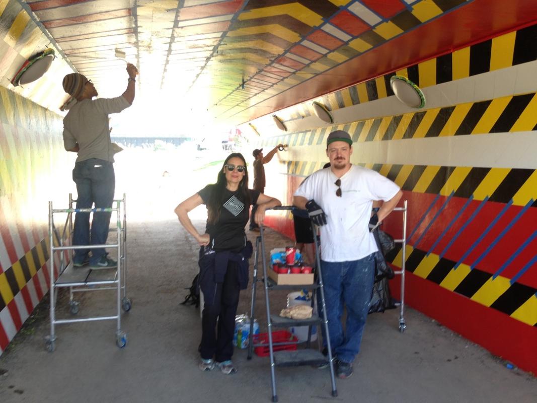 Artist and assistants working on public art in an underpass