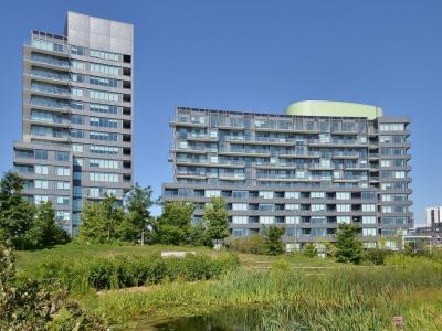 a photo of two condo buildings taken from a park on a sunny blue sky day