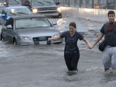 cars stuck and people walking through flooded streets