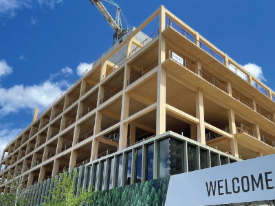 A mass-timber building under construction. Timber frame in foreground and blue sky in background.