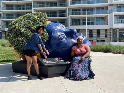 two artists pose in a park with their latest piece of public art