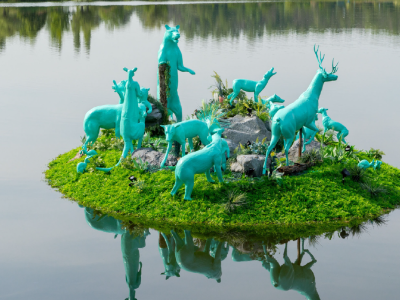 Art installation with model animals all painted blue on a floating island.