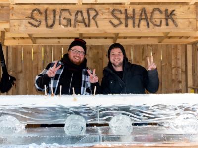 two people at an outdoor booth in front of large block of ice