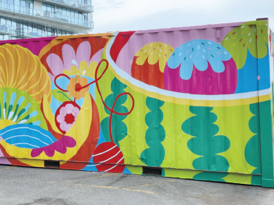 A mural-covered shipping container in a parking lot. 