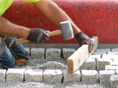 A construction worker laying granite pavers. 