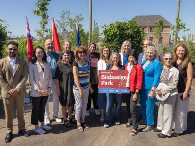 Group photo from the official opening of a new park. One dignitary holds a sign saying "Welcome to Biidaasige Park".