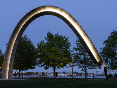 A large public art arch is activated by the artist and lit up at night