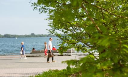 A view someone walking along the water's edge with Lake Ontario in the background