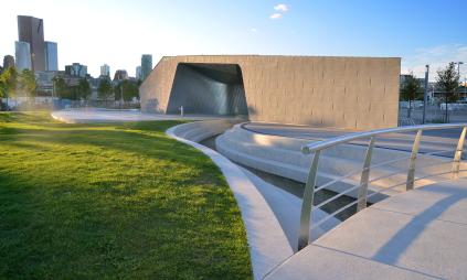 a concrete pavillion and open green space at an urban park