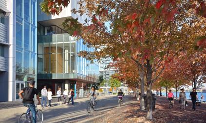 people walking and cycling on the water's edge promenade in the fall